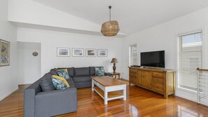 A living room with a grey sofa, wooden coffee table, and a TV on a wooden cabinet.