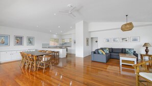 A spacious living area with a dining table, sofas, and a kitchen in the background.