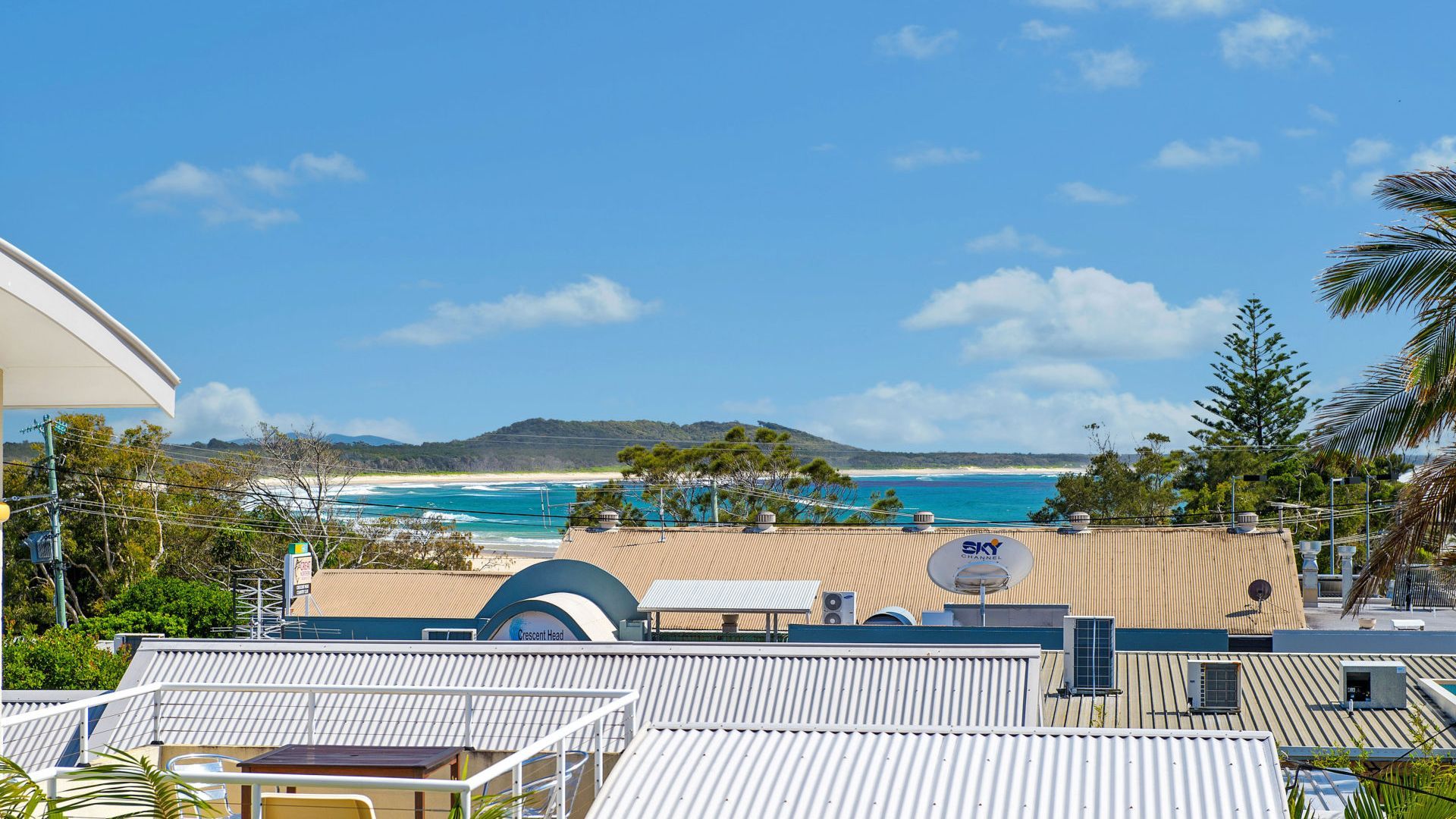A coastal view with a beach, ocean, and hills in the distance.