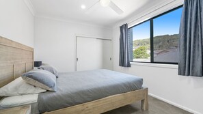 A bedroom with a bed, a door, and a window with curtains.