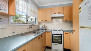 A compact kitchen with wooden cabinets, a built-in oven, and a stainless steel sink.