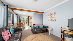 A modern living room with a leather sofa, a dining table, and a small side table.
