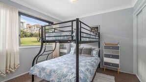 Habitación con literas y vistas a un jardín y casas.