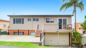 Een woonhuis met twee verdiepingen, een garage, een balkon en een palmboom.