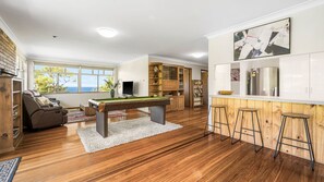 A modern living space with a pool table, bar area, and a view of the outdoors.