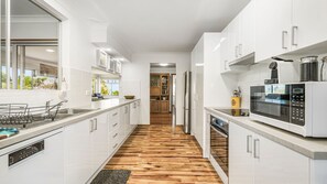 A modern kitchen with white cabinetry, a wooden floor, and a built-in microwave.
