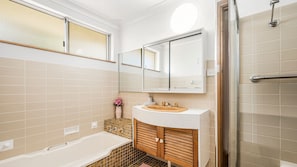 Un bagno moderno con una vasca, un lavandino con uno specchio sopra e uno spazio doccia.
