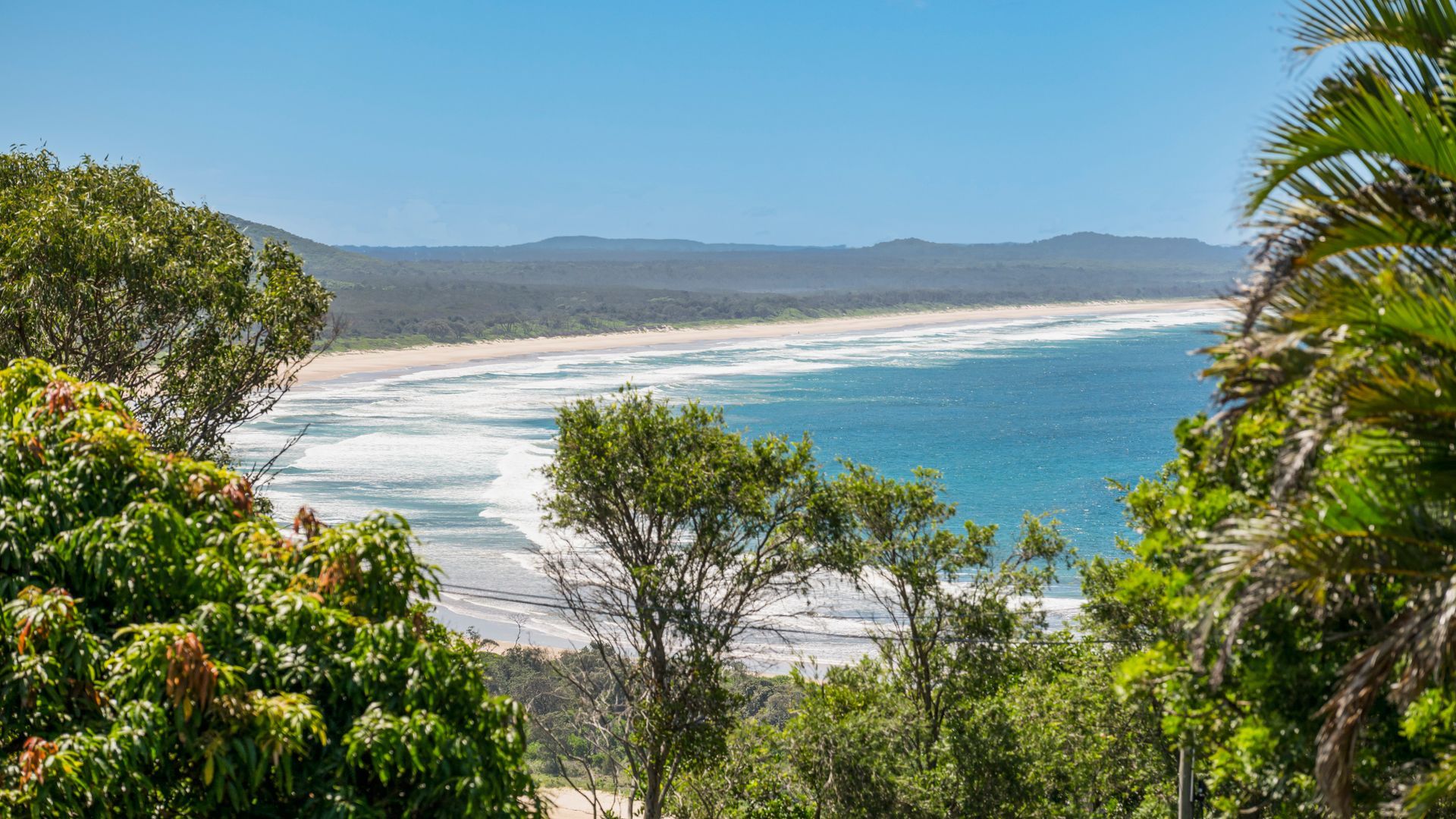 A coastal landscape with a beach, ocean, and surrounding vegetation.