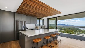 A modern kitchen with a large island, bar stools, and a view of a landscape.