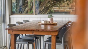 A wooden dining table with six chairs, a potted plant, and a tray with a candle. - Sea Salt, 24 Stewart Street (Crescent Head)