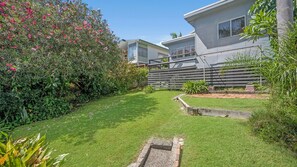 A residential property with a well-maintained lawn, a wooden fence, and a variety of flowering plants. - Sea Salt, 24 Stewart Street (Crescent Head)