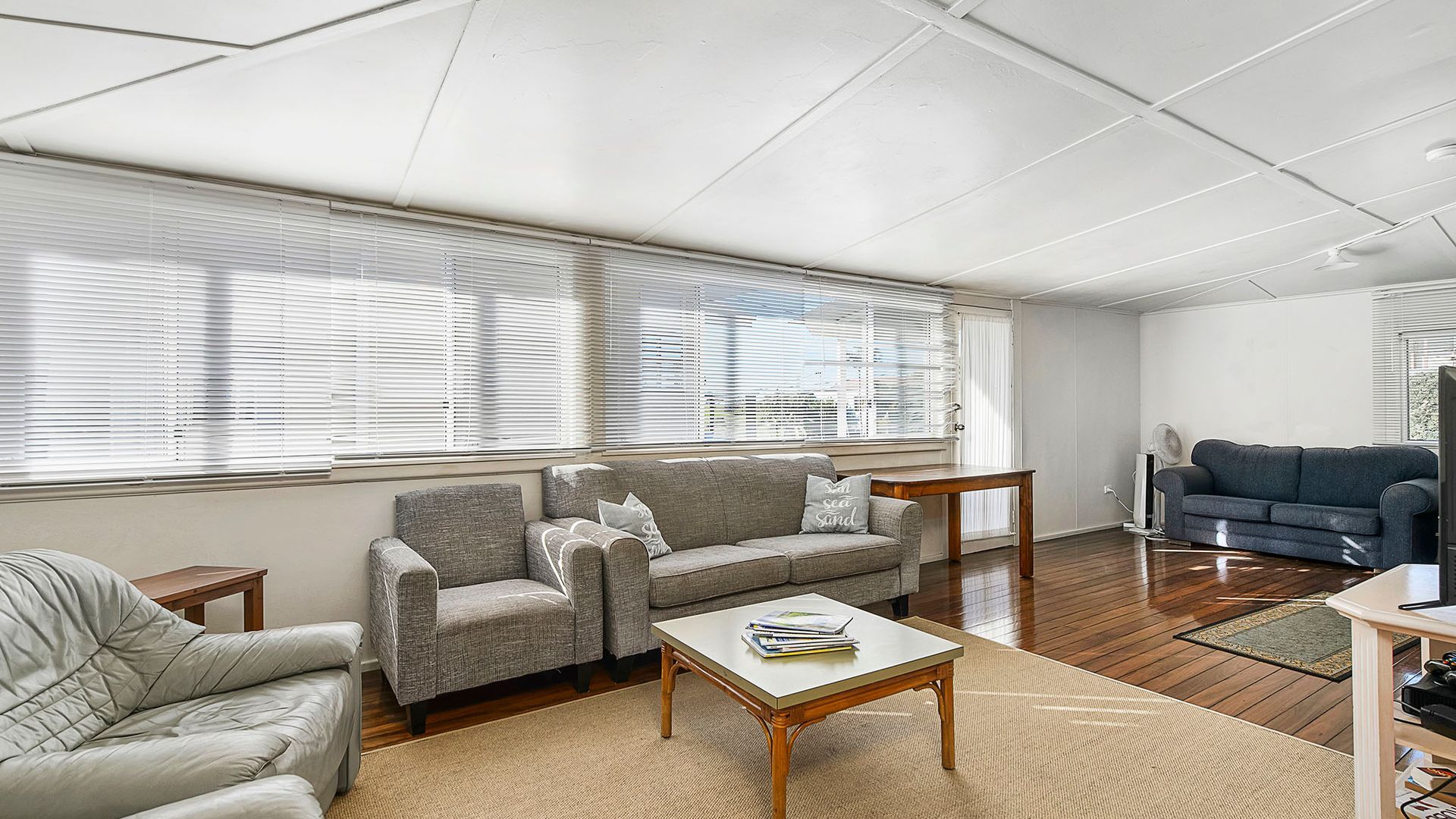 A living room with a sofa, armchair, coffee table, and a television.