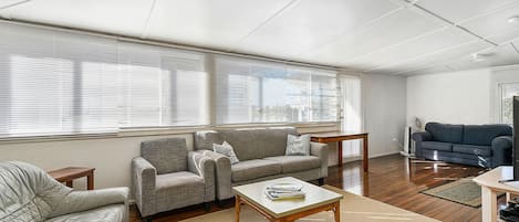 A living room with a sofa, armchair, coffee table, and a television.