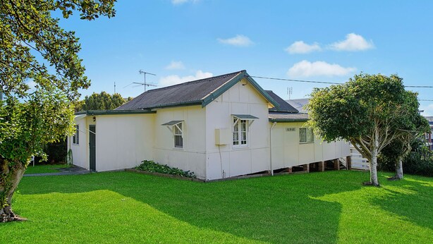 Uma casa térrea com telhado empena e varanda frontal, com gramado bem cuidado.