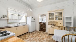 A compact kitchen with a stove, refrigerator, and dining area with chairs and a table.