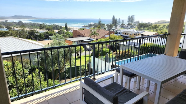 A balcony with a view of the ocean and a swimming pool.