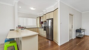 A modern kitchen with a central island, stainless steel appliances, and a window with blinds.