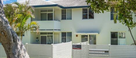 A two-story building with a flat roof, large windows, and a gated entrance.