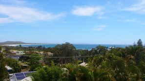 Eine Küstenlandschaft mit Blick auf das Meer, Vegetation und ein Gebäude mit Solaranlage.