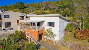 Una moderna casa a due piani con un balcone, una scala che conduce al piano superiore e vista sul paesaggio circostante.