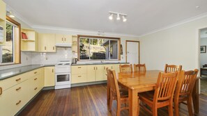 A kitchen with wooden cabinets, a stove, and a dining table with chairs.