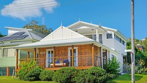 Une maison à deux étages dotée d’un balcon, de panneaux solaires et d’un jardin bien entretenu.