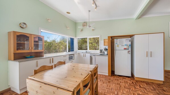 A compact kitchen with a dining area, wooden cabinets, a built-in microwave, and a refrigerator.