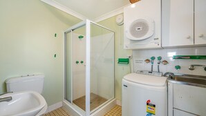 Un baño con ducha de vidrio, inodoro, lavamanos y calentador de agua.