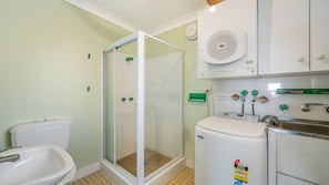 Een badkamer met een douchecabine, toilet, wastafel en een boiler.
