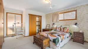 A bedroom with a bed, bedside tables, a wardrobe, a mirror, and a ceiling fan.