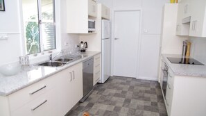 A kitchen with white cabinets, a stainless steel sink, a microwave, and a refrigerator.