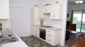 A compact kitchen with white cabinetry, a built-in oven, and a countertop with a sink.