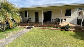 Una casa con un patio techado, césped y una palmera.