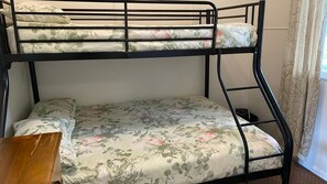 A bunk bed with floral bedding and a wooden side table.