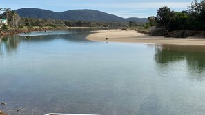 Un río con una playa arenosa y una persona remando.