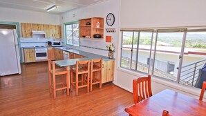 Een moderne keuken met houten kastjes, een centraal kookeiland met barstoelen, een magnetron en een klok aan de muur.