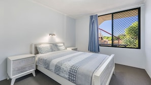 A bedroom with a bed, nightstands, a window with a view, and a ceiling light. - Beachfront 1, 25 Willow Street (Crescent Head)