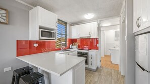 A modern kitchen with white cabinetry, a microwave, a toaster, and a sink.