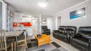 A modern living room with a sofa set, a wooden coffee table, and a dining area with a table and chairs.
