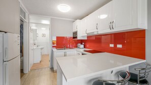 A modern kitchen with white cabinets, a red backsplash, and a central island with seating.