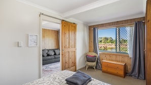 Una camera da letto con un letto, un armadio in legno, una finestra che si affaccia su un paesaggio naturale e una porta che conduce in un'altra stanza.