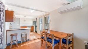 A compact kitchen with a dining area, wooden furniture, and a visible clock.