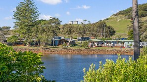 Una propiedad junto al lago con cabañas, un muelle y una colina al fondo.