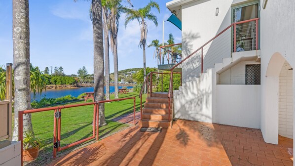 A staircase leading to a balcony with a view of a body of water and palm trees.