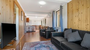 Una sala de estar moderna con un sofá de cuero negro, un televisor de pantalla plana y una alfombra estampada.