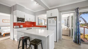 A modern kitchen with white cabinetry, a central island, and a view to a balcony with a pool.