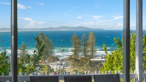 A coastal view with a clear sky, ocean, and trees.