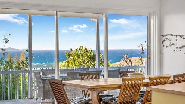 A dining area with a view of the sea and hills. - Beau Soleil, 28 East Street (Crescent Head)
