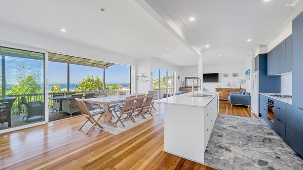 A modern kitchen with a large island, a dining area with a view, and a living space with a TV.
