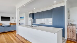 A modern kitchen with a central island, built-in appliances, and a large window.